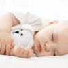 Carefree sleep little baby with a soft toy on the bed